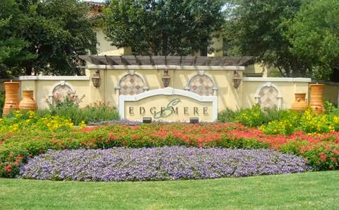 Entrance sign reading 'Edgemere' surrounded by manicured flower beds, decorative urns, and trees.