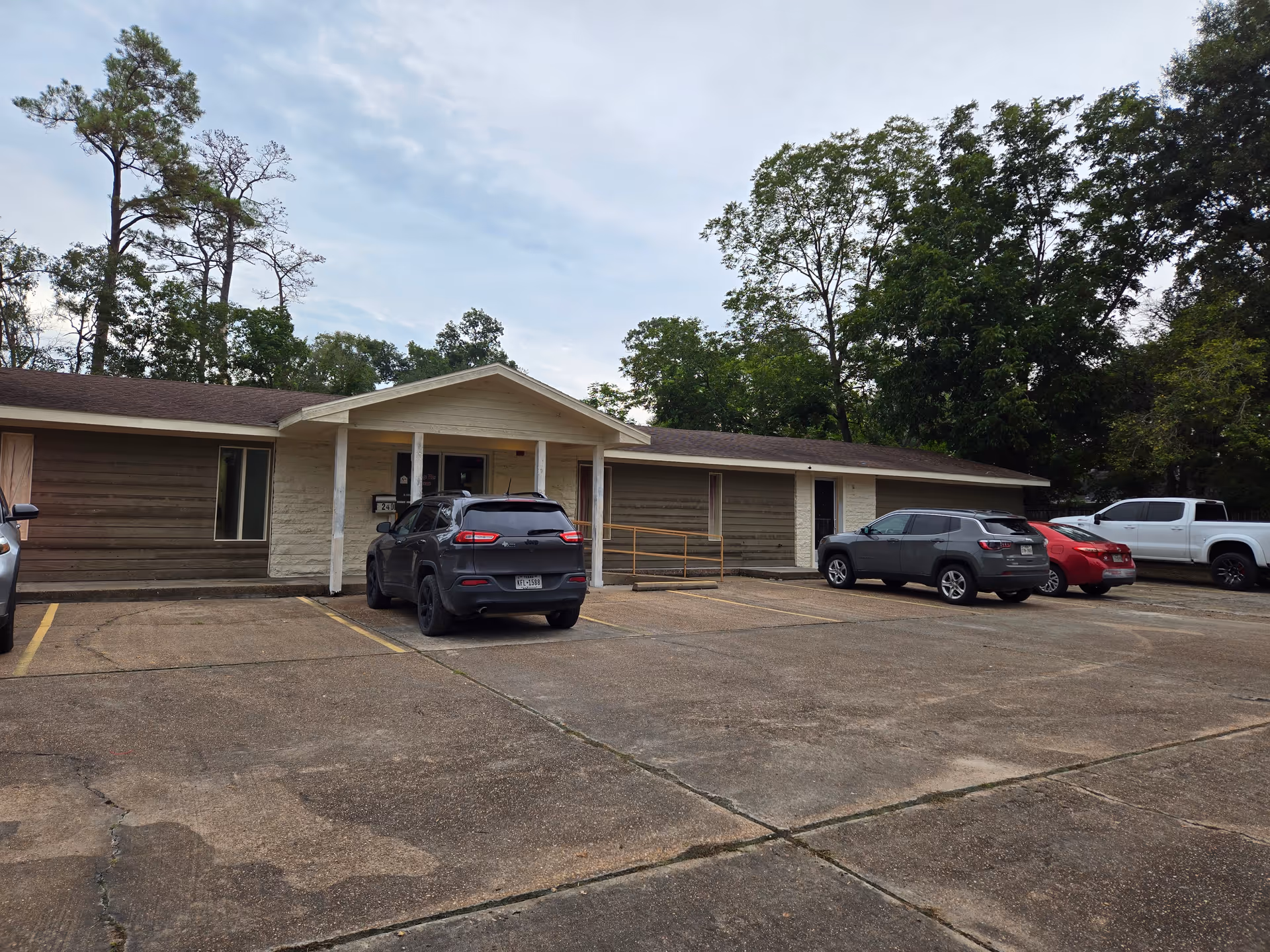 Single-story building with a small front entrance and parked cars in front.