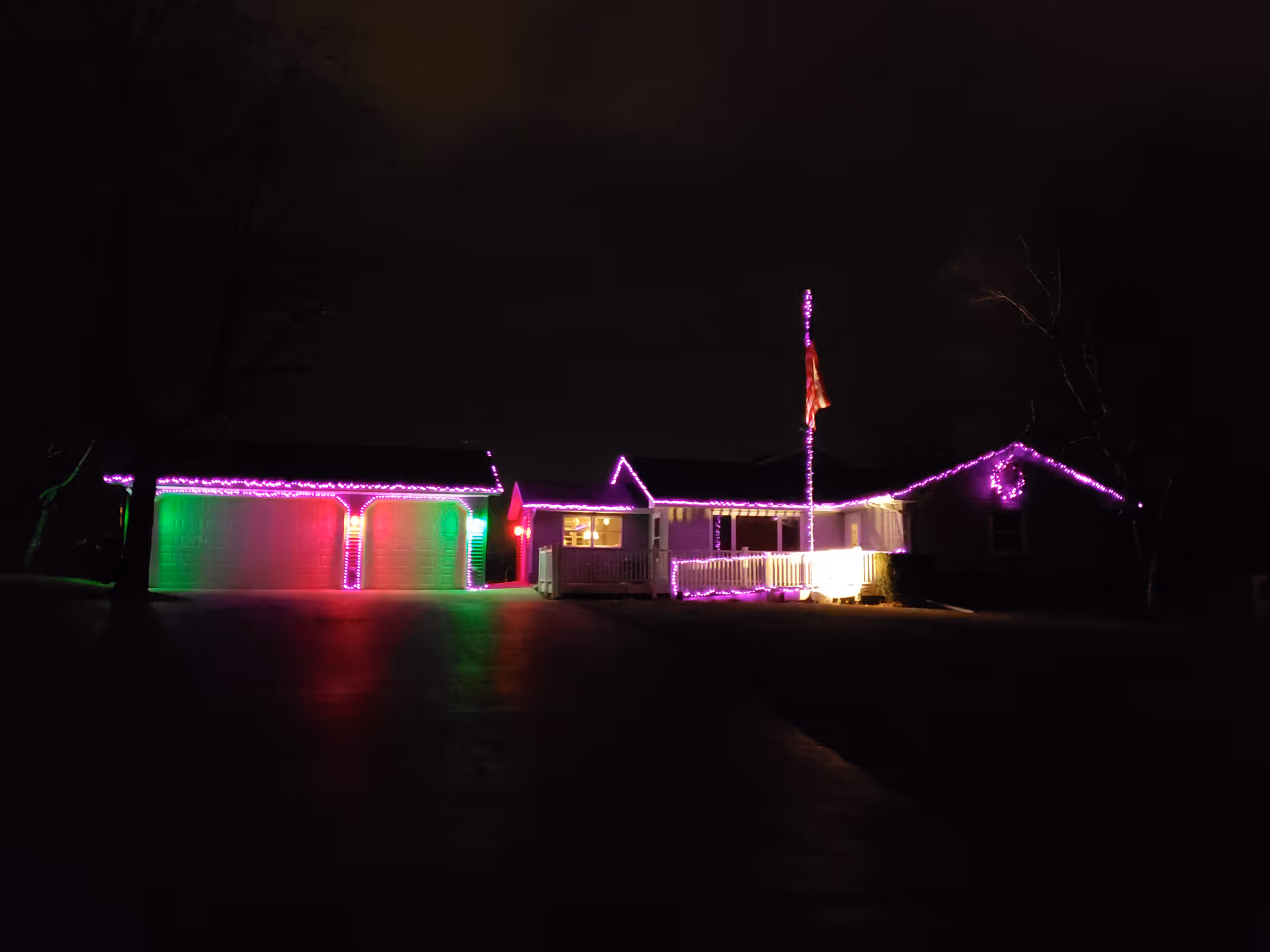 Dark night exterior of a single-story house adorned with colorful holiday lights.