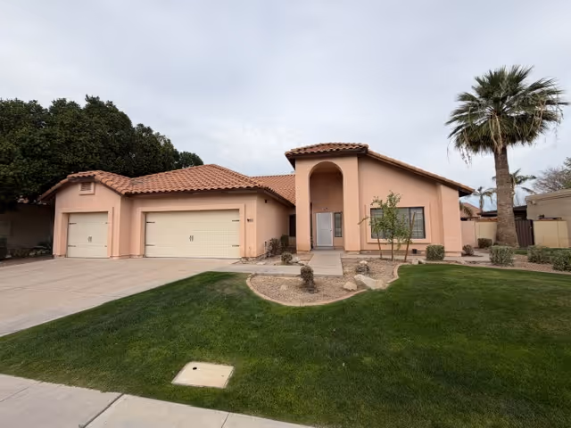 Pink stucco senior care home with a two-car garage and manicured front yard