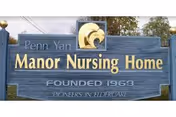 Blue outdoor sign for Penn Yan Manor Nursing Home displaying Founded year and motto.