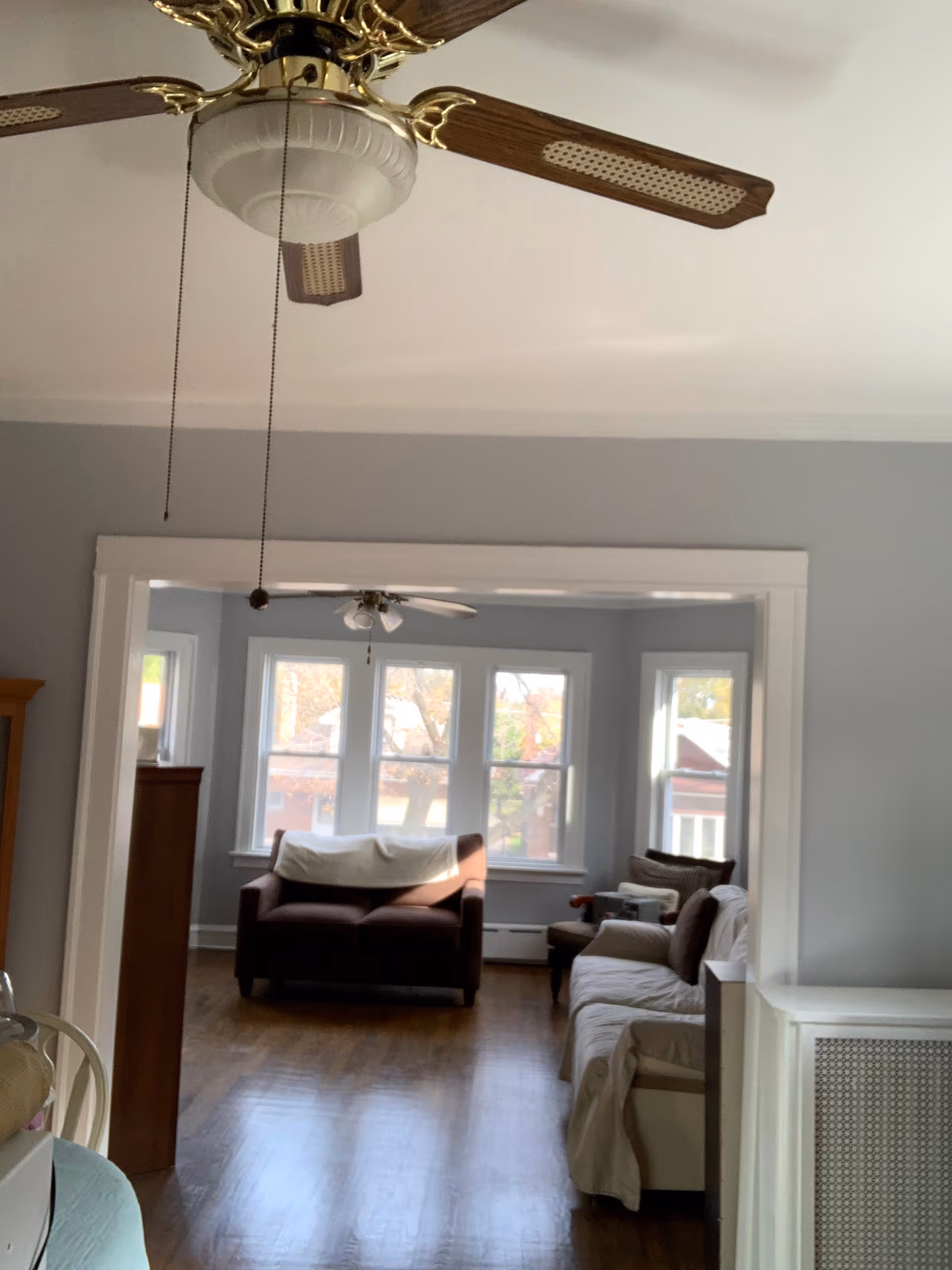 Living room with sofas, large windows, and ceiling fans in a bright space.