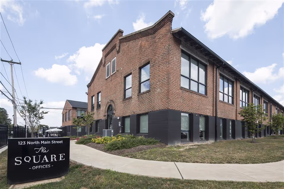 Exterior brick building with large windows and a curved sidewalk in front.