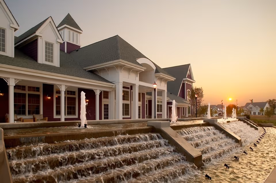 A large building at sunset with columned porches and tiered cascading fountains in the foreground.