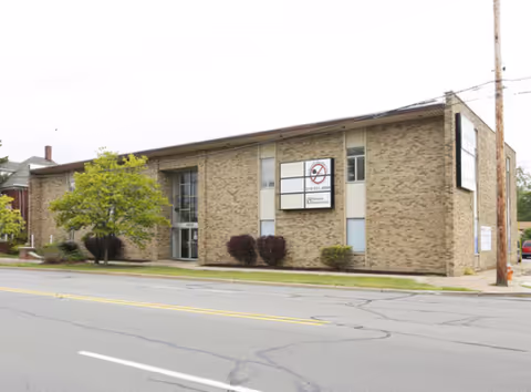 Beige brick care facility building with Beacon of Light Care sign on a street.
