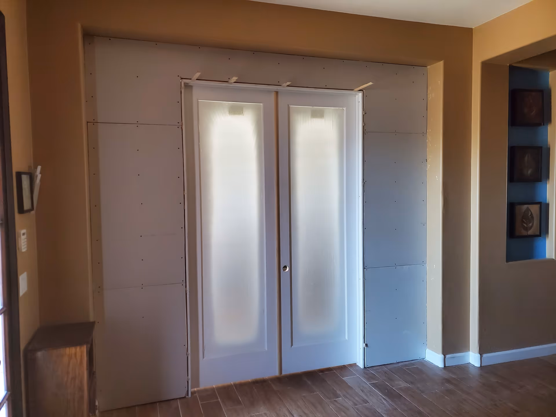 Interior hallway with frosted double elevator doors under construction and unfinished walls.