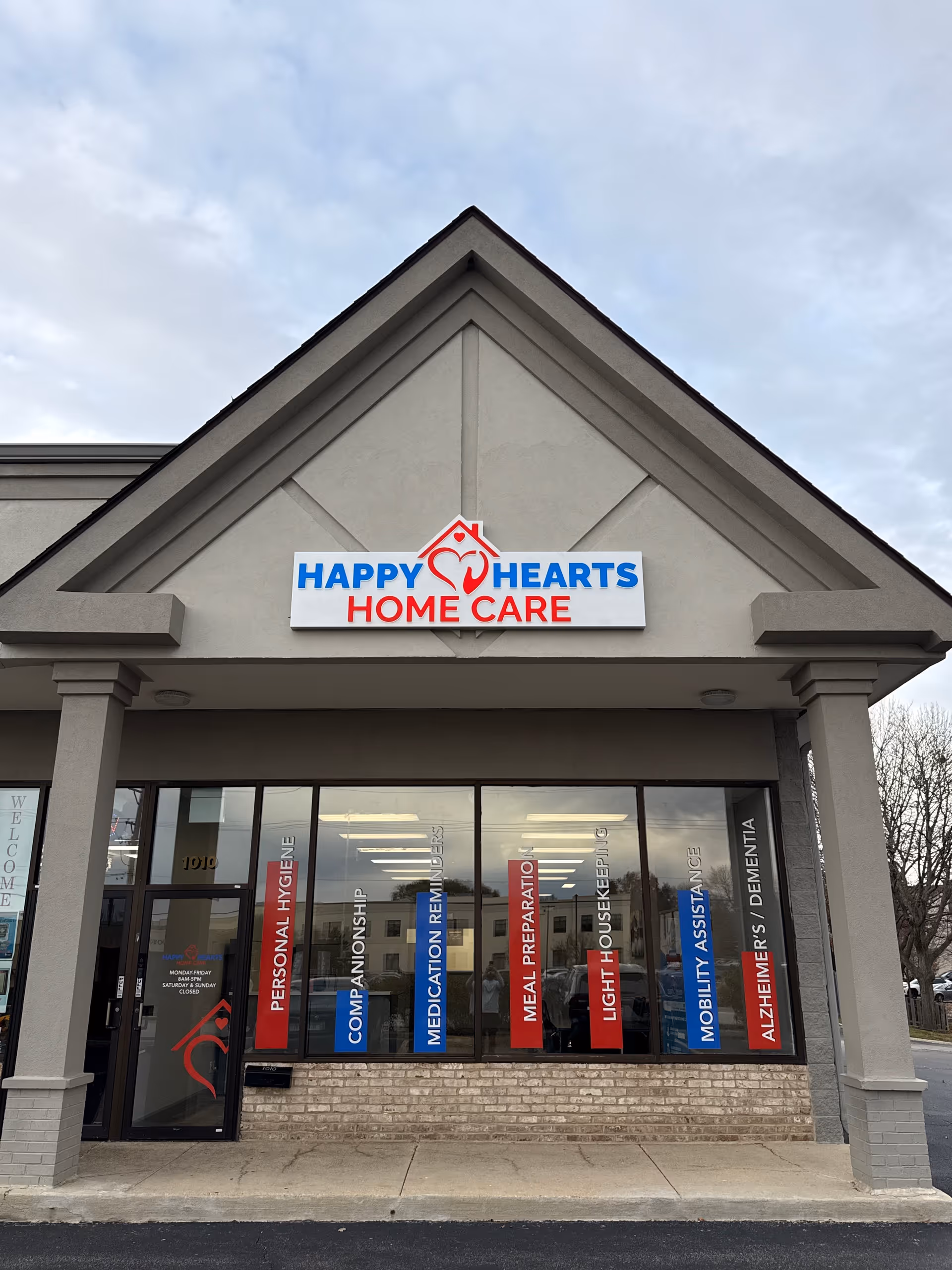 Exterior storefront of Happy Hearts Home Care with sign, pillars, and glass windows.