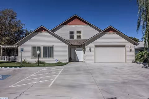 Front view of a single-story senior living facility with two garage bays and a paved driveway