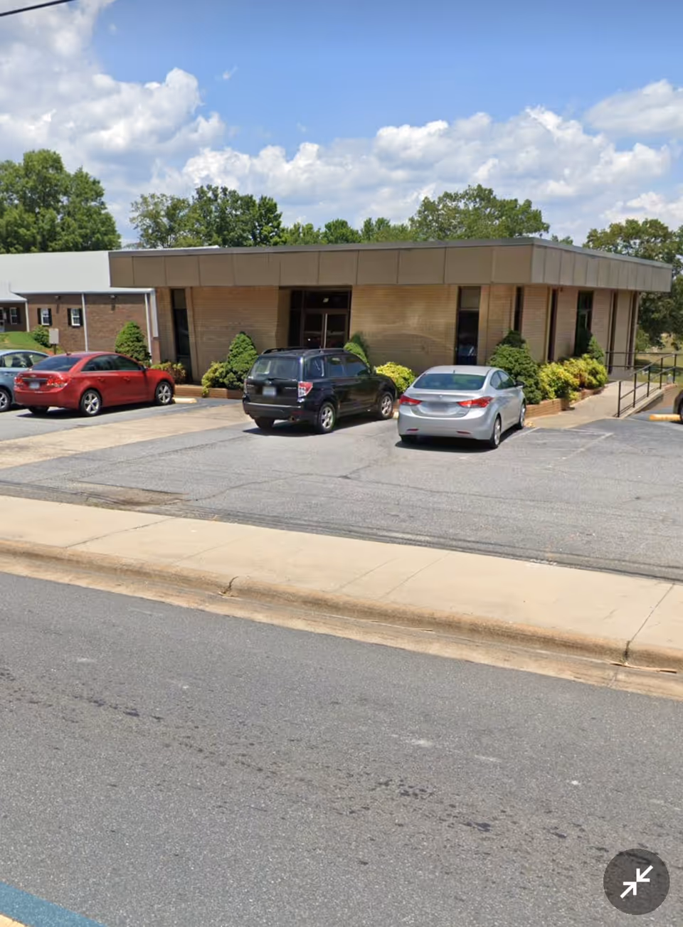 Front view of Premier HomeCare facility with brick exterior, metal awning, and parked cars.