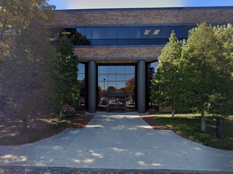 Front entrance of a senior services facility with glass doors and surrounding trees.
