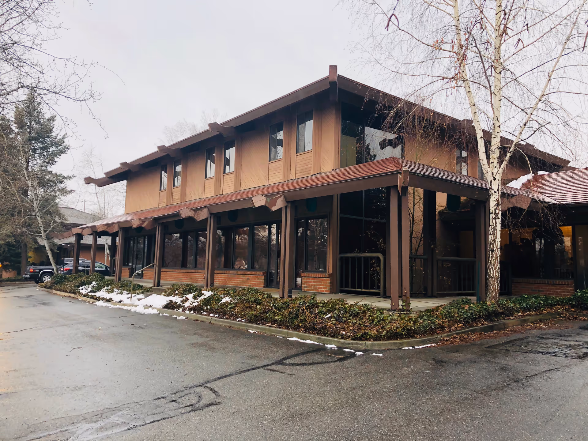 Exterior view of a brown, modern senior care facility with a covered entrance and large windows.