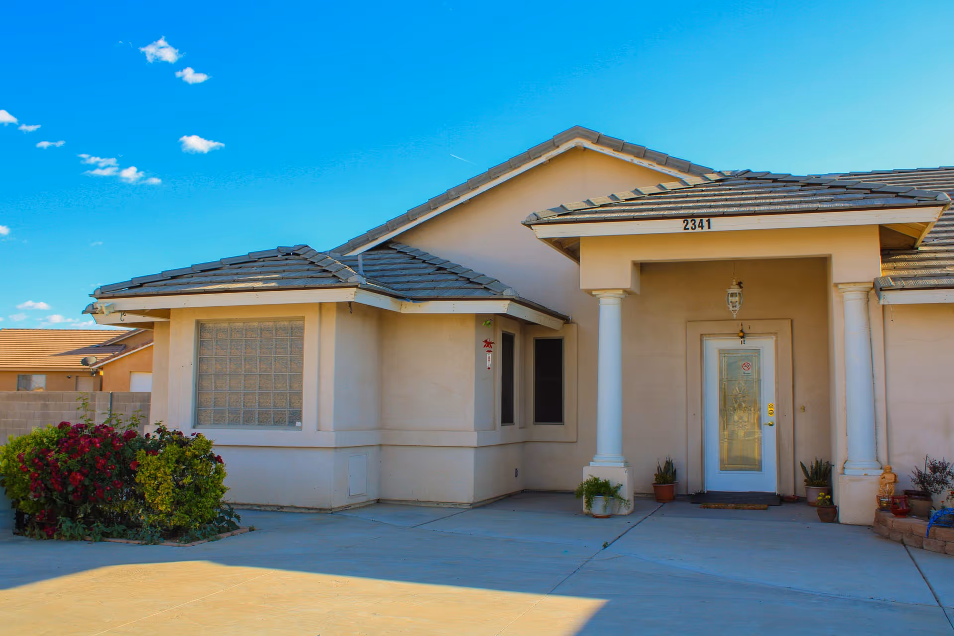 Single-story assisted living facility entrance with columns and a glass front door