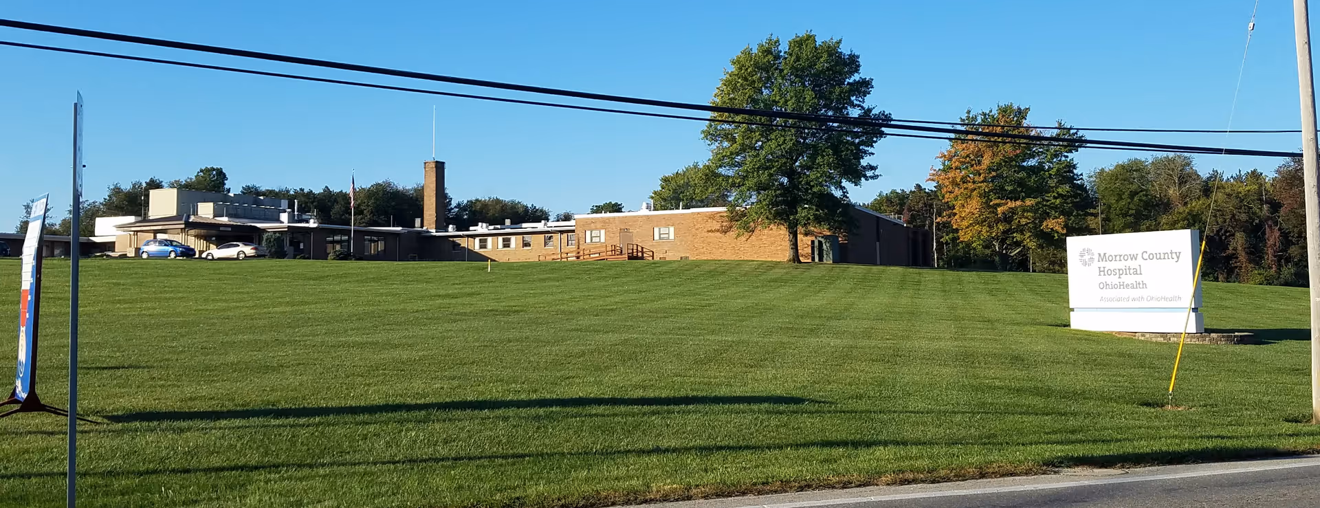 Exterior view of a brick hospital building with a grassy lawn and sign.