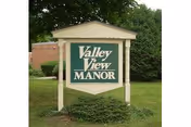 Sign for Valley View Manor Nursing Home on a grassy lawn with trees.