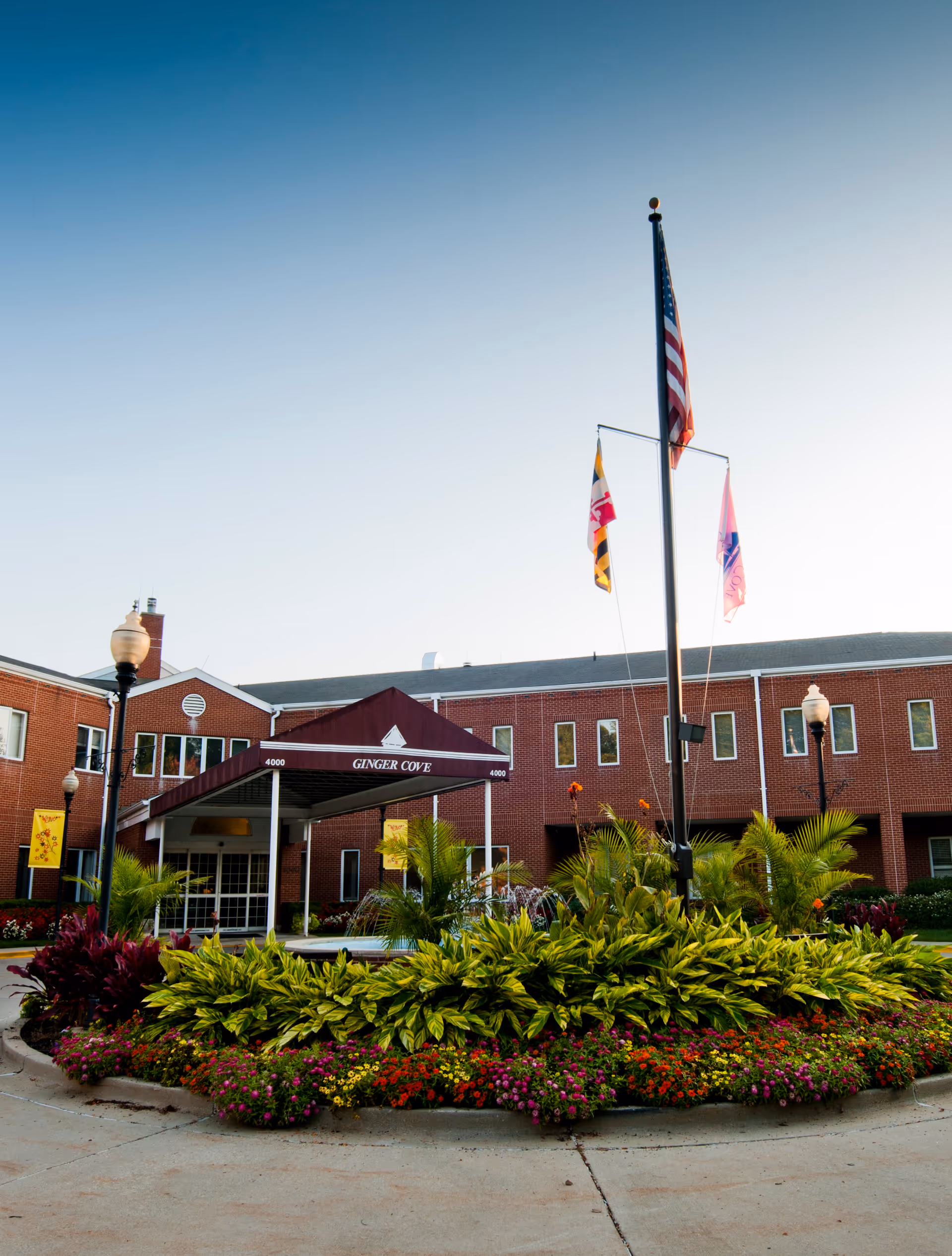 Brick Ginger Cove senior living facility exterior with a covered entrance and landscaped garden.