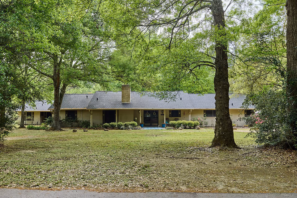 Exterior view of a single-story senior living facility front amid trees and a grassy lawn.