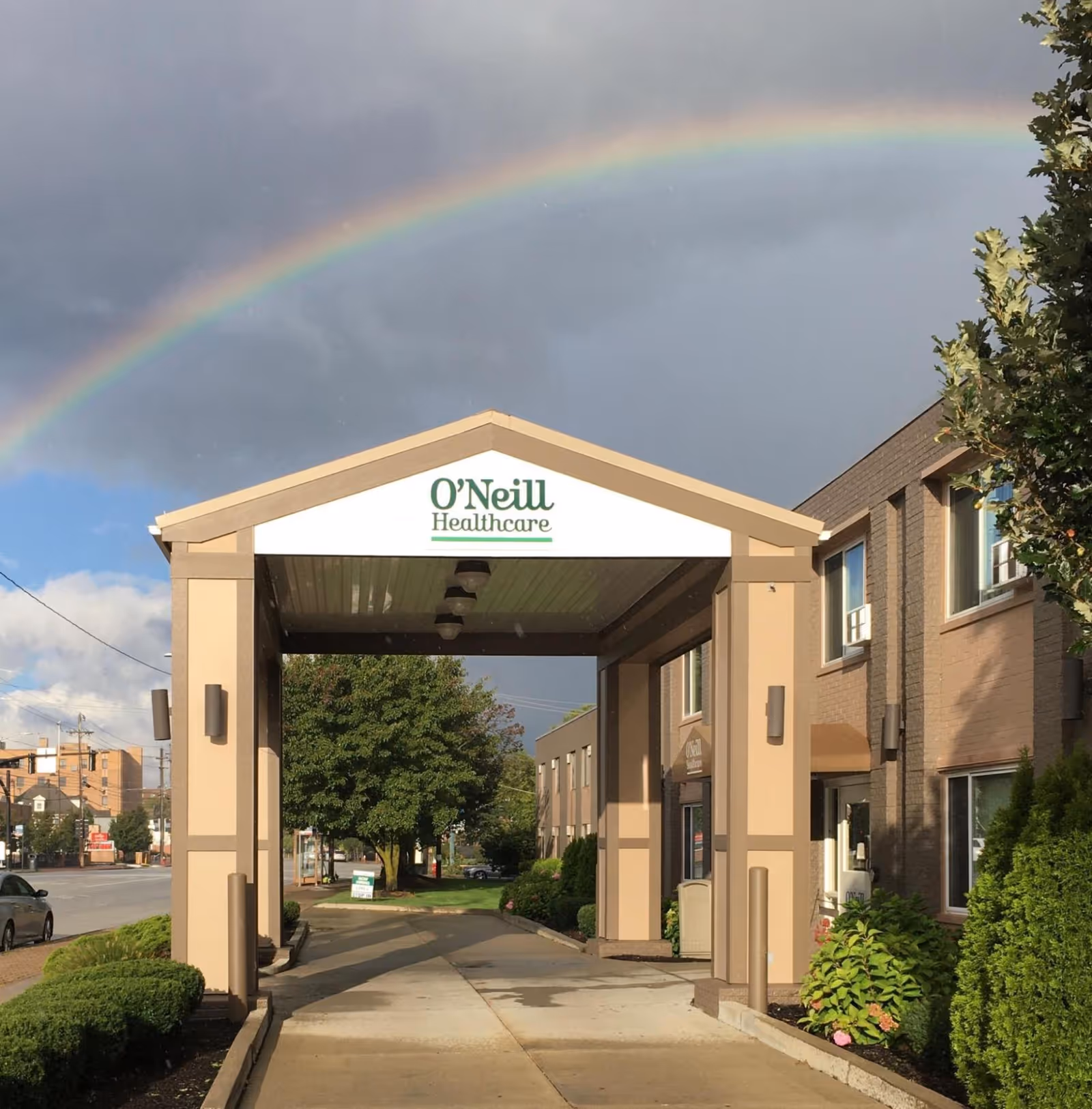 Exterior view of O'Neill Healthcare Lakewood entrance with a rainbow overhead