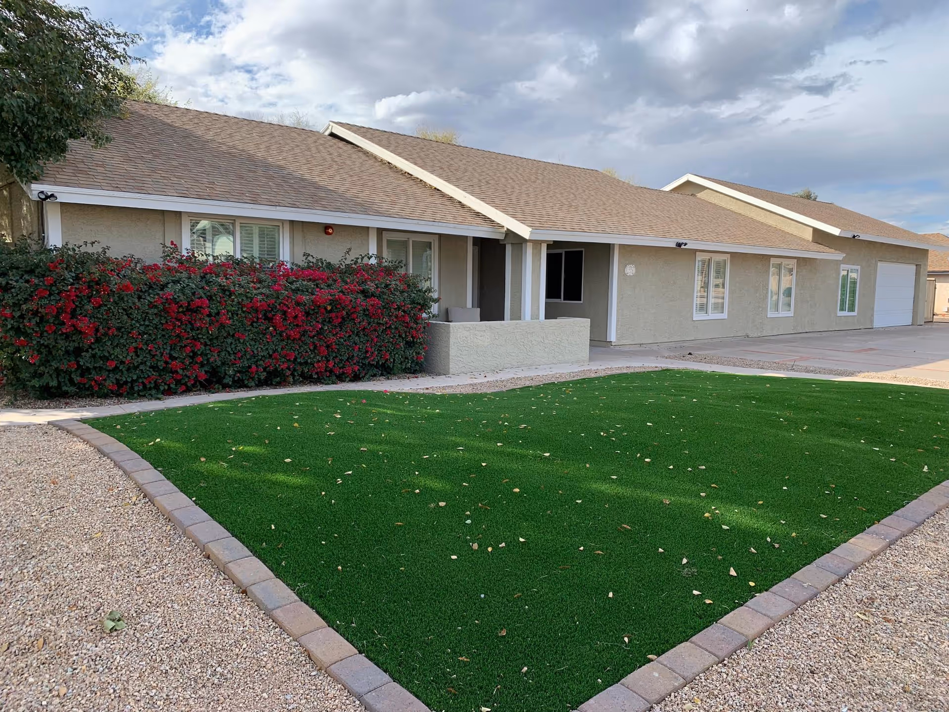 Single-story senior living facility exterior with manicured green lawn and shrubs