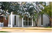 Front entrance of a nursing center with columns, glass doors, and flowering trees.