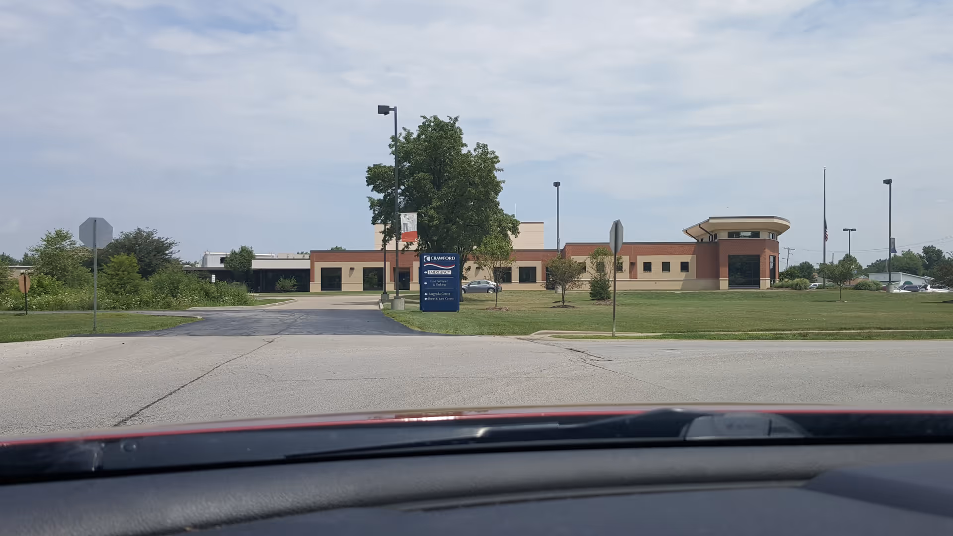 Wide exterior view of Crawford Memorial Hospital building across a grassy lot, seen from a car.