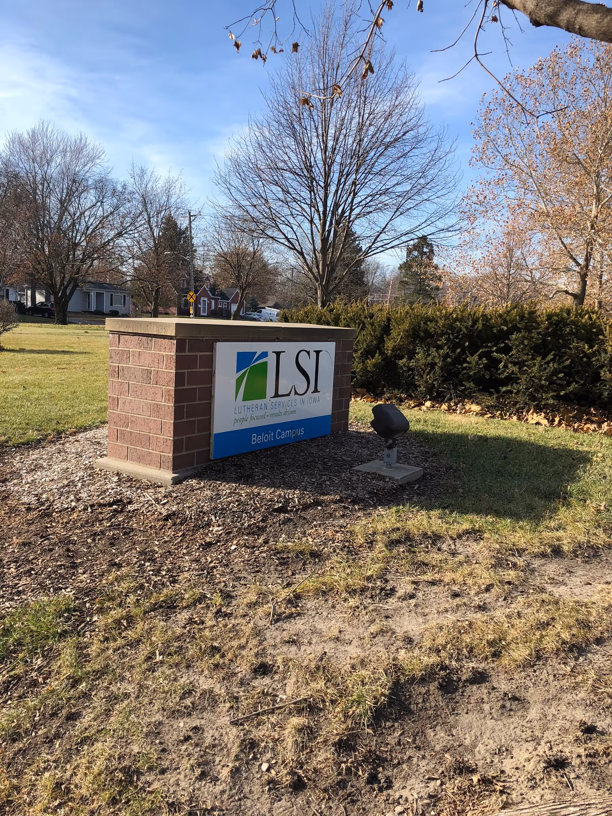 Outdoor sign for Lutheran Services in Iowa Beloit Campus amid trees and shrubs