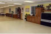Bright open common area with wooden cabinets, a TV, and scattered seating.