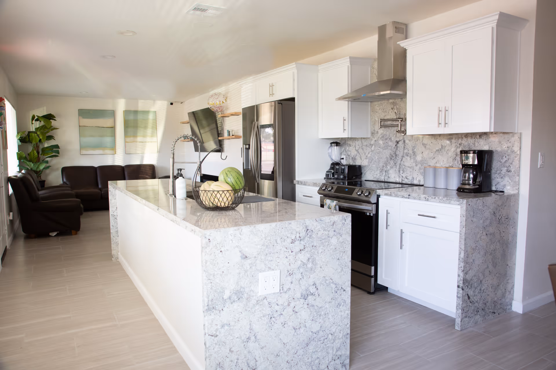Bright modern kitchen with white cabinets, granite countertops, stainless appliances, and a seating area.