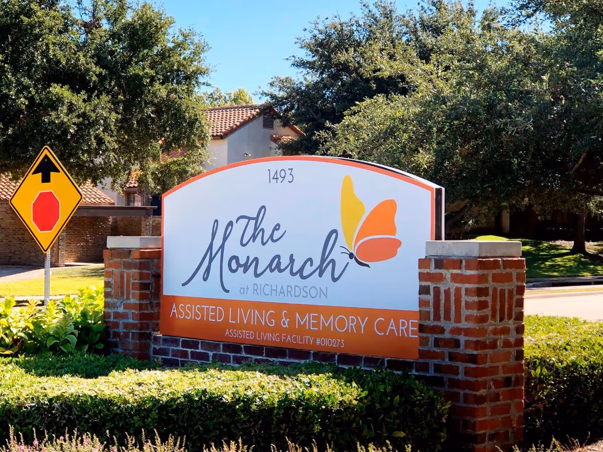 Exterior view of Monarch at Richardson entrance sign with brick columns and landscaping.
