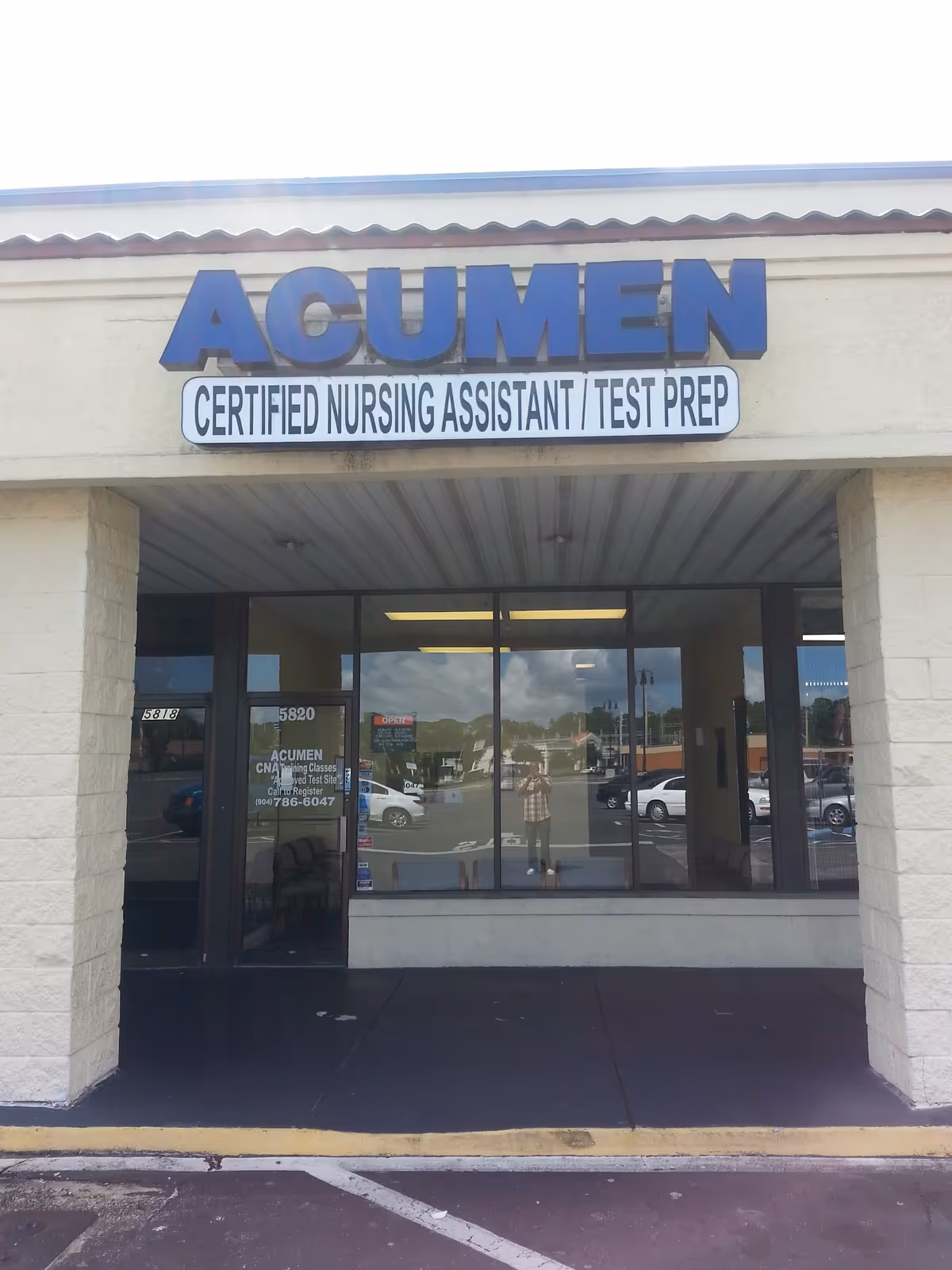 Front view of ACUMEN entrance sign for CNA training with glass doors.