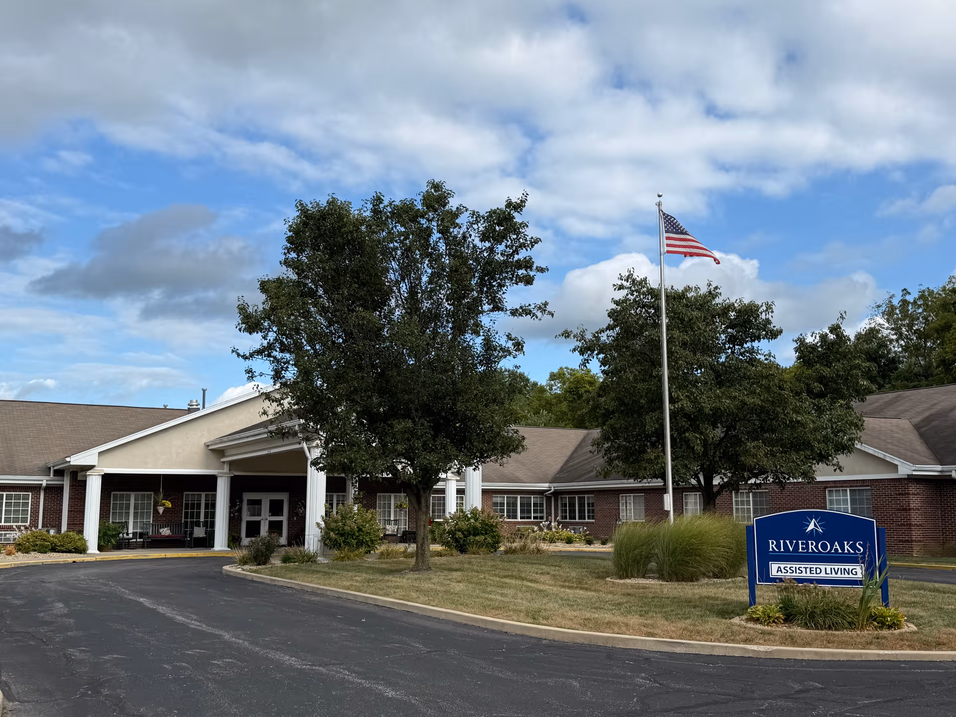 Single-story brick senior living campus with a RiverOaks sign and American flag.
