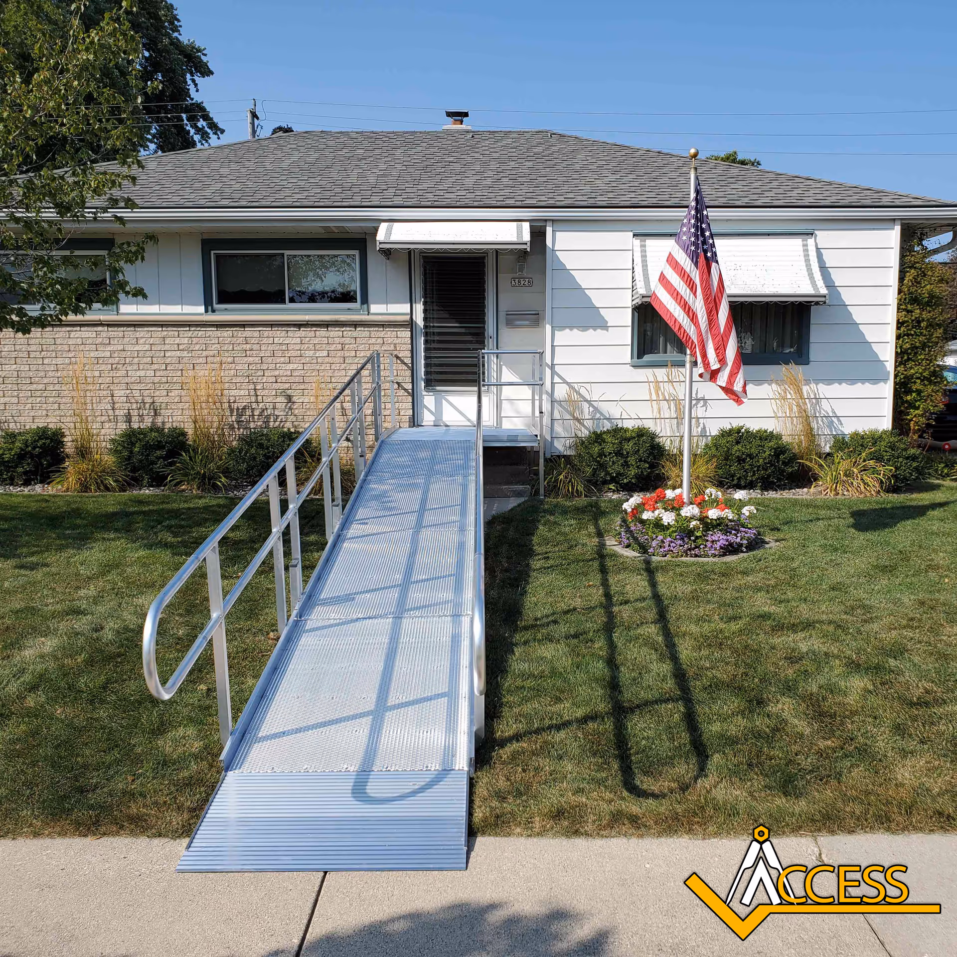 Accessible ramp leads to a single-story building with an American flag and landscaped front yard.