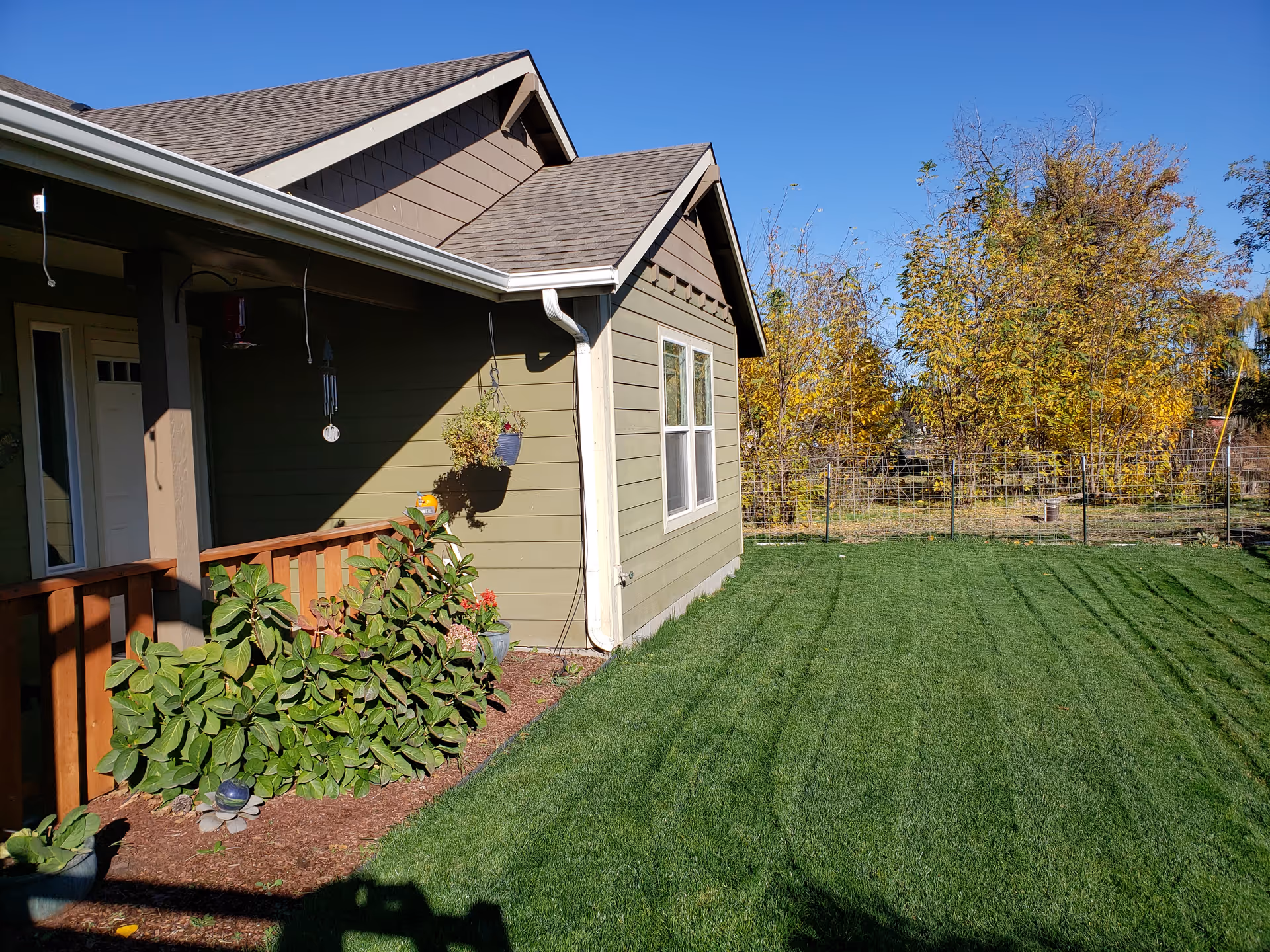 Exterior view of The Geneva House Adult Foster Home with green lawn and trees.