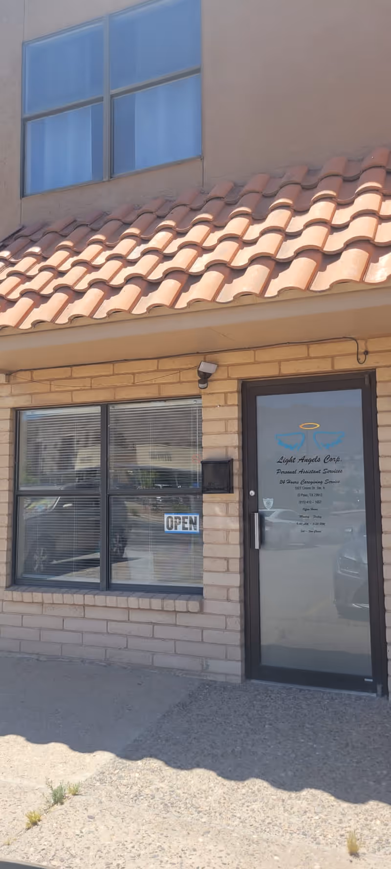 Exterior view of Light Angels Care entrance with open sign, brick wall, and tiled roof.