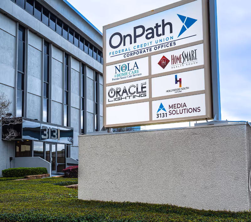 Exterior of a commercial building with a tall sign displaying multiple tenants.