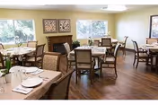 A bright dining room with multiple tables, chairs, and place settings near windows.