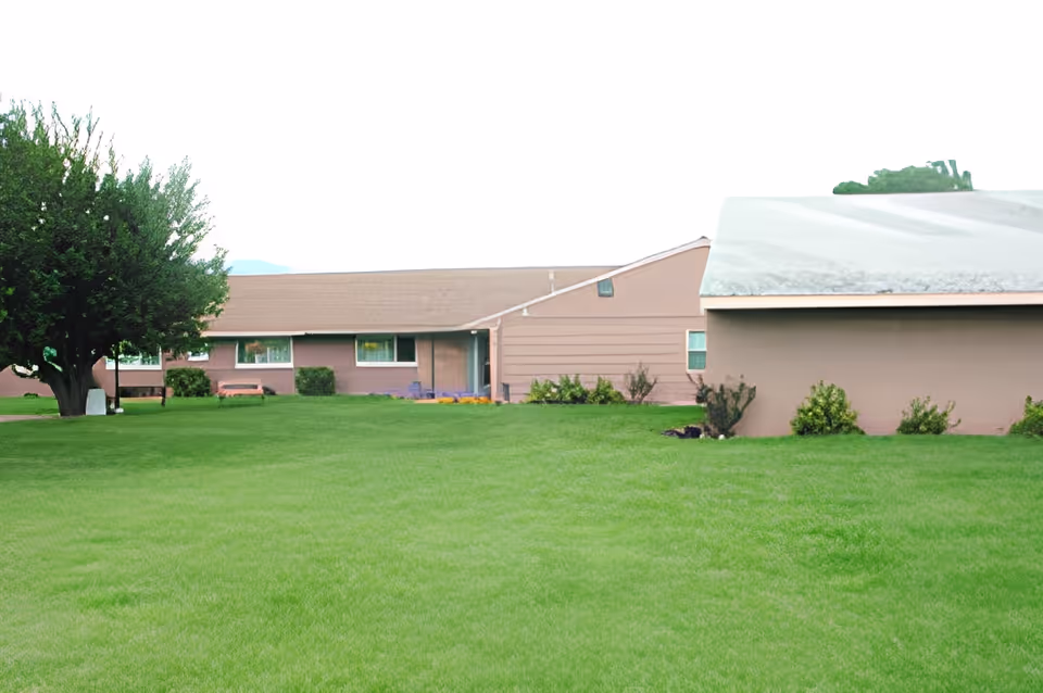 A view of the Meadows Assisted Living Center with buildings surrounded by lush green lawn and trees.