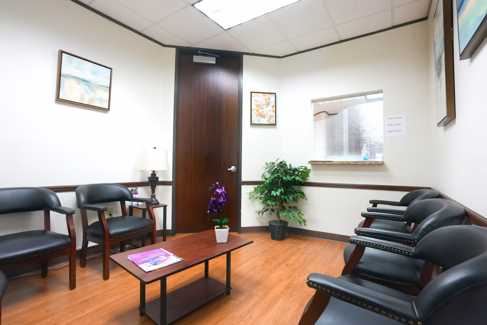 A quiet Familiar Medical Center waiting area with black chairs, a table, and a plant.