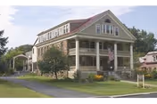 Front view of Holton Memorial Home, a two-story senior living house with a wraparound porch.