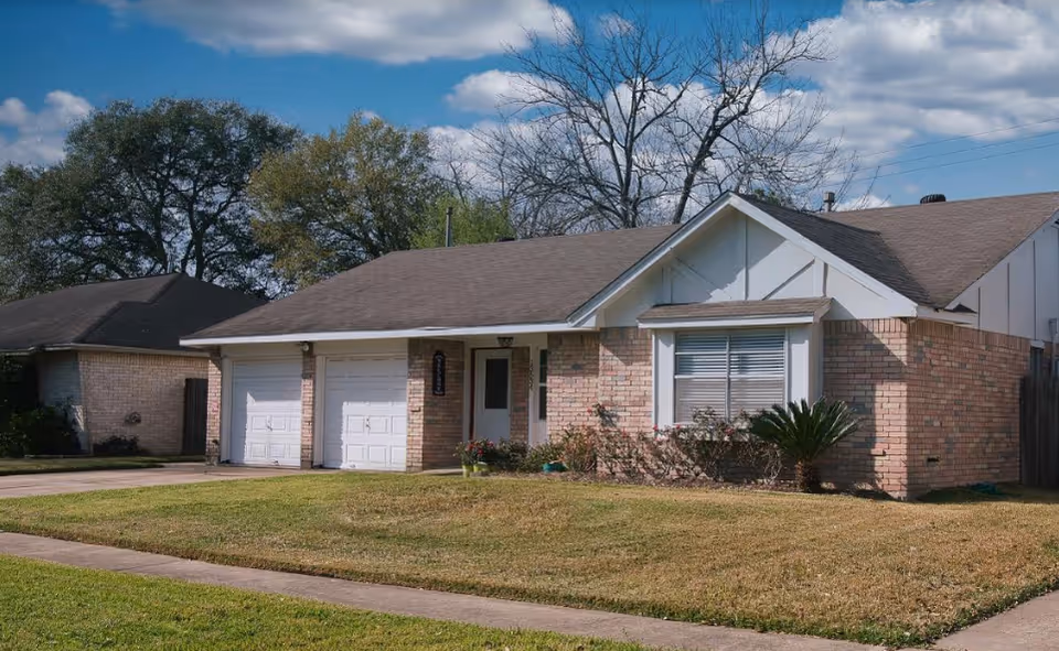 Front view of a single-story brick building with two garage doors and a lawn.