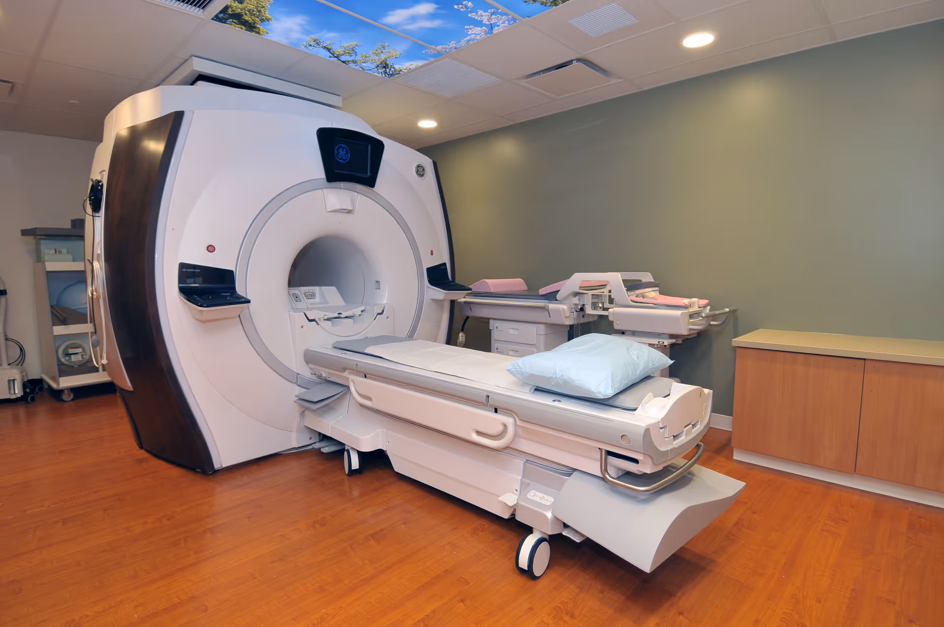 MRI machine with examination table in a clean, well-lit medical imaging room.