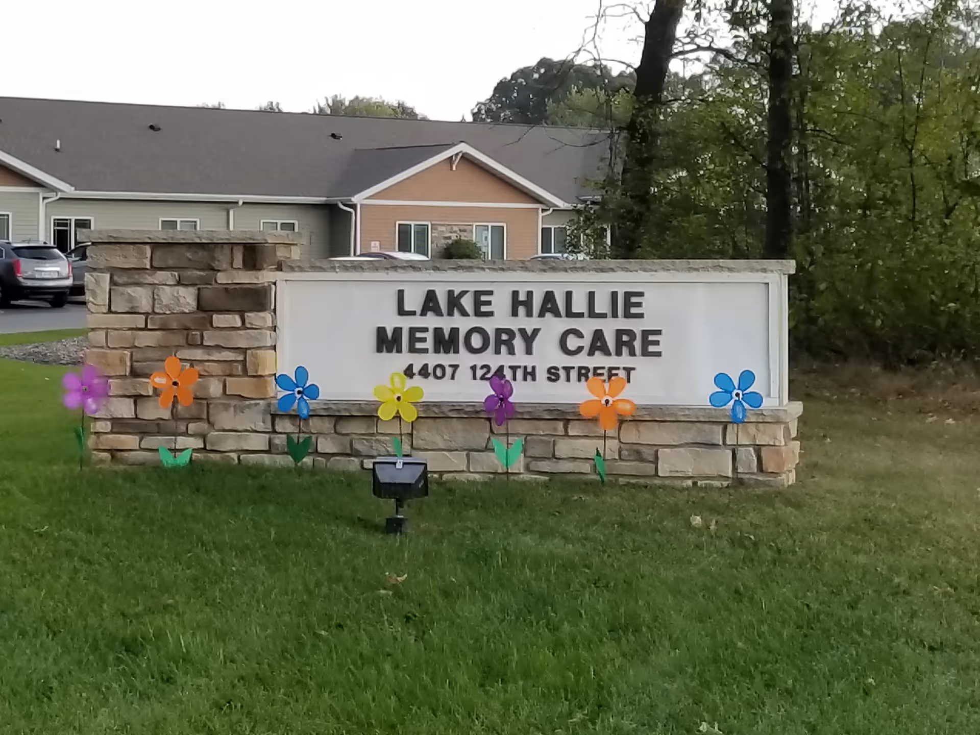 Lake Hallie Memory Care sign on stone base with colorful flowers outside building