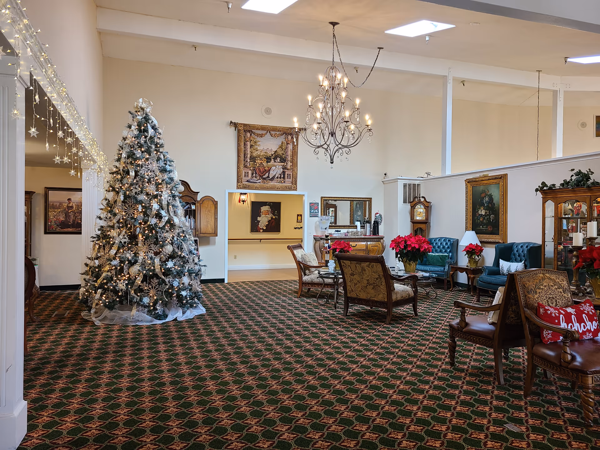 Spacious senior living lobby with a large Christmas tree, chandeliers, and ornate seating.