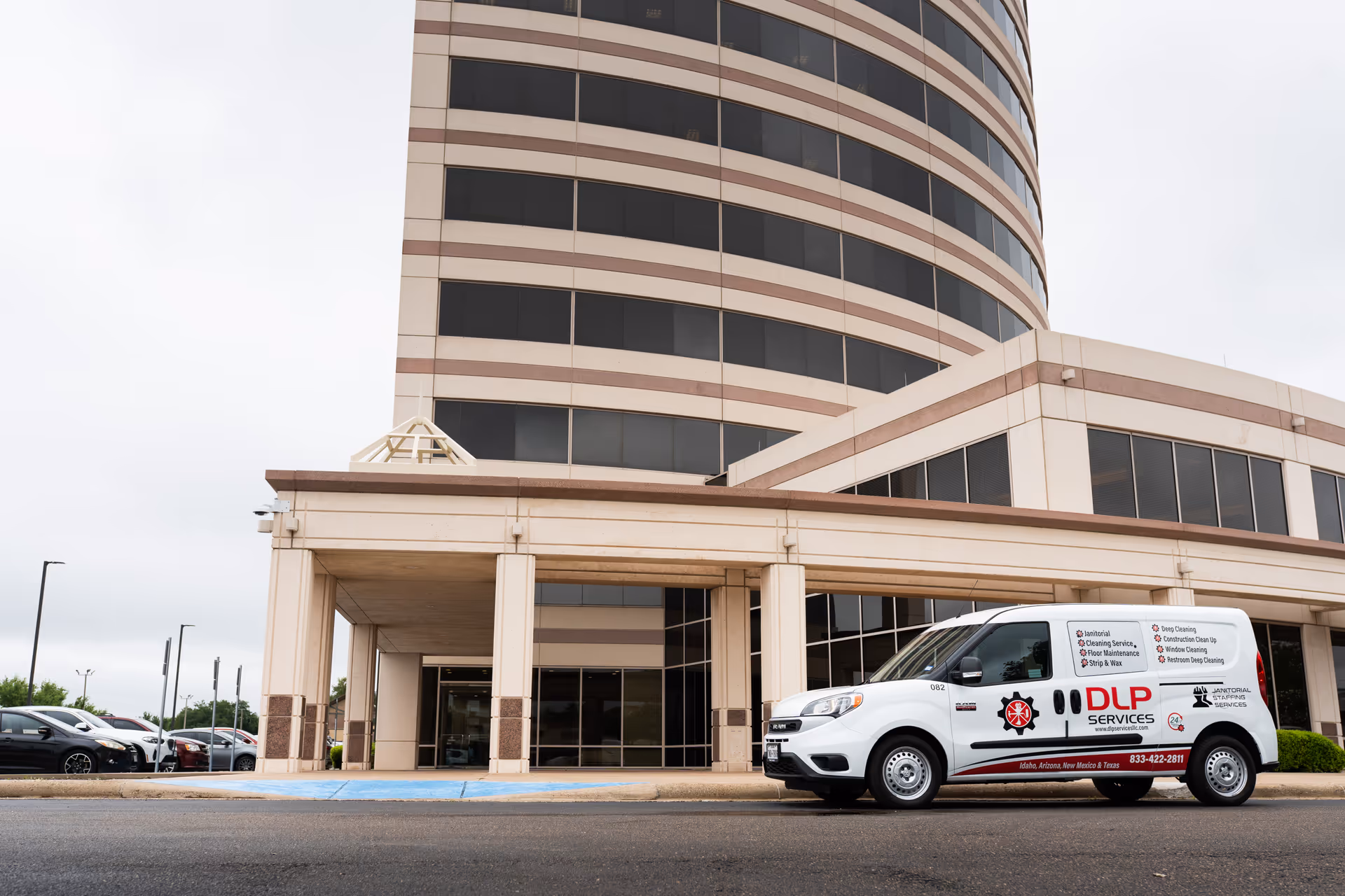 Exterior view of a multi-story beige building with a white DLP Services van at the entrance.