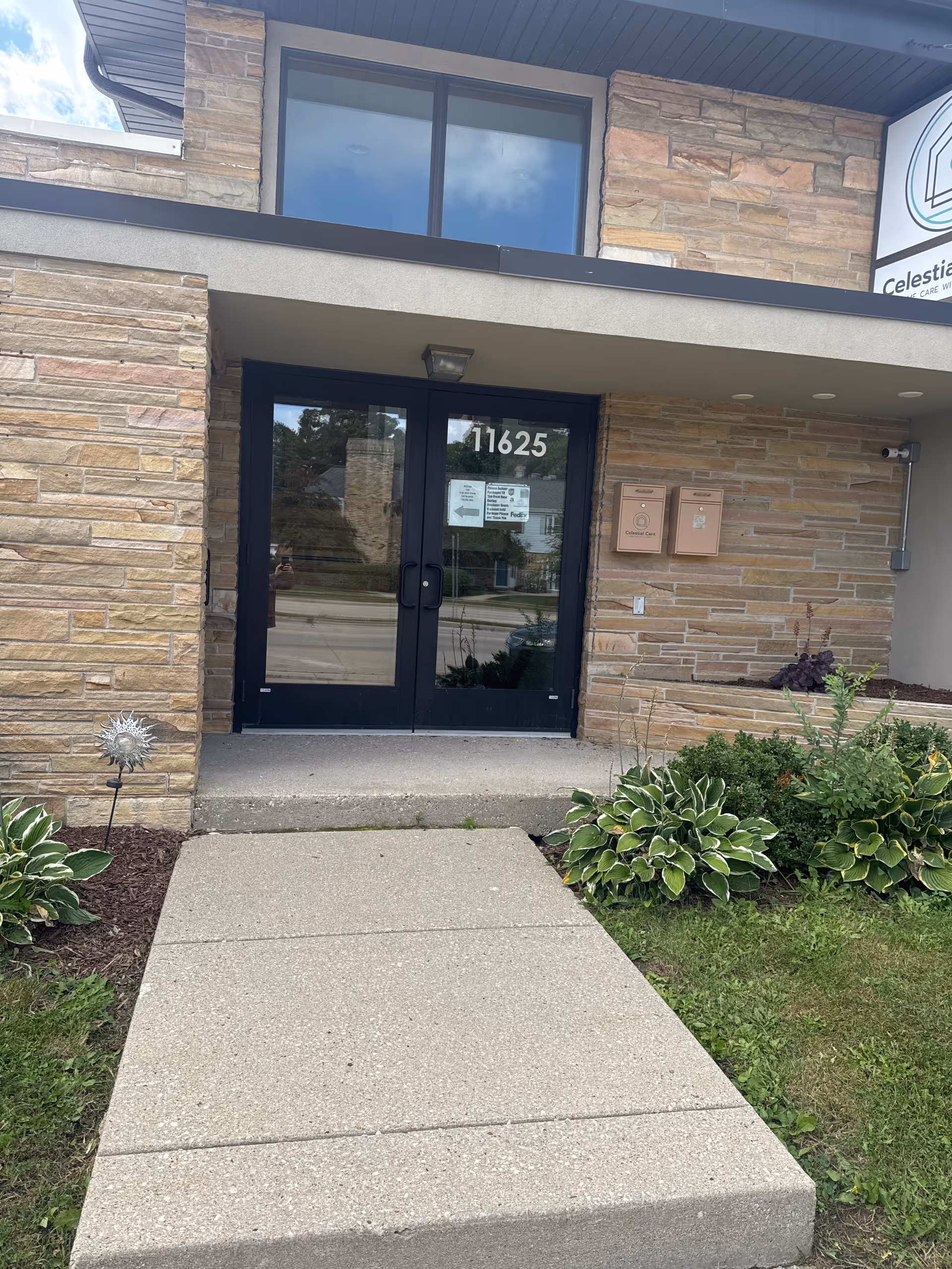 Exterior view of Celestial Care entrance with stone facade and glass doors.
