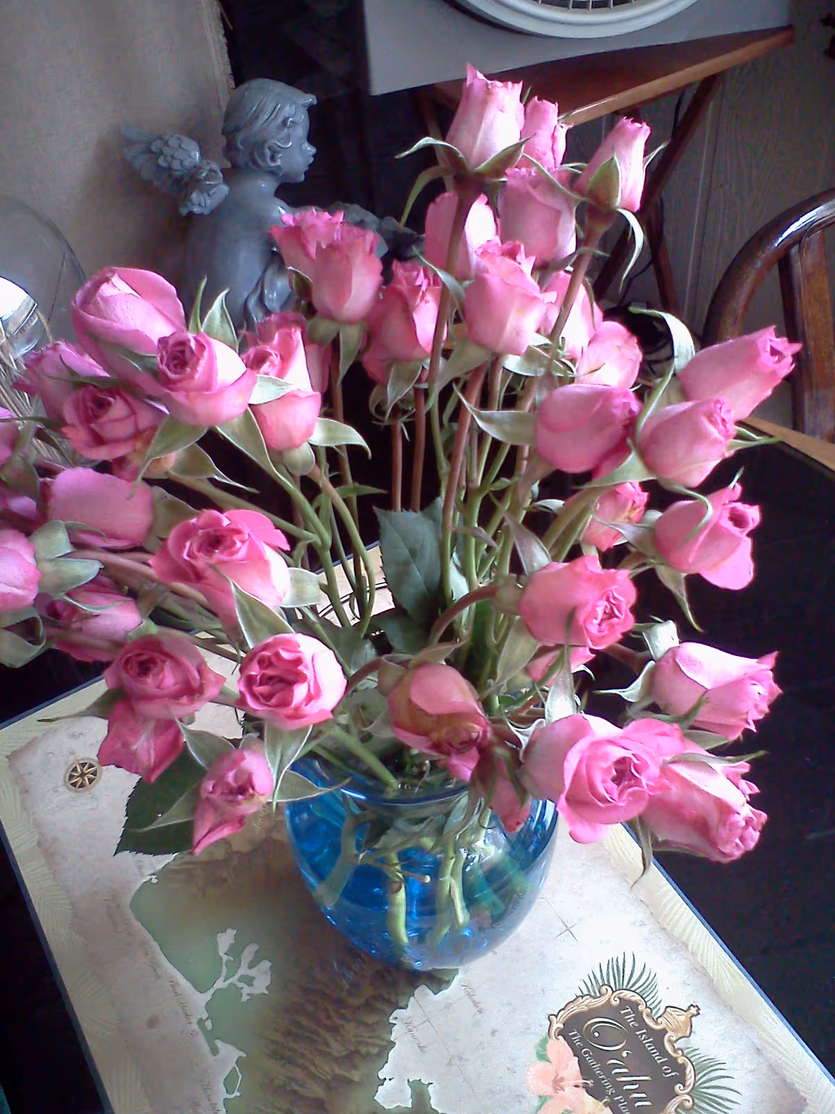 Bouquet of pink roses in a blue vase on a decorative table indoors.