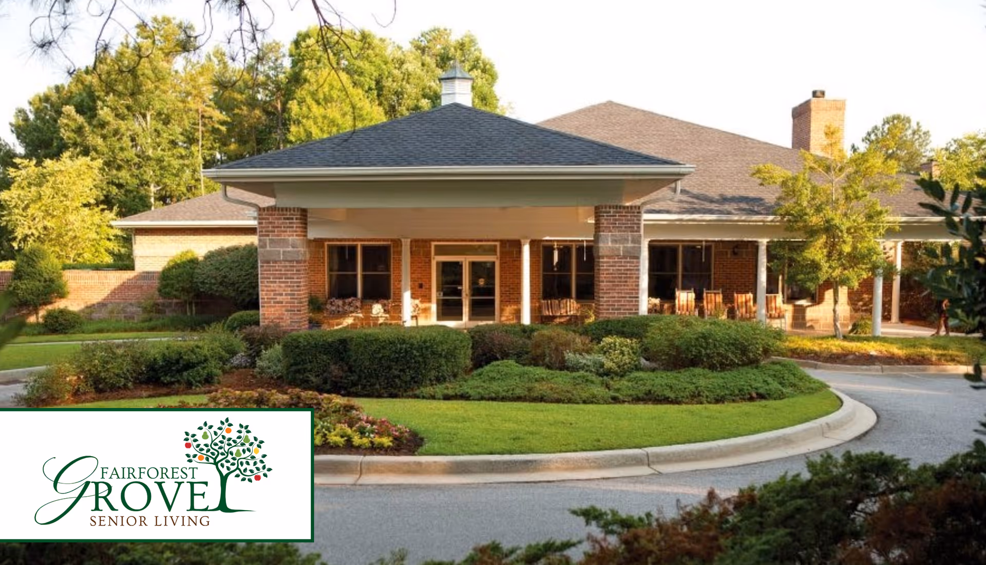 Front entrance of a single-story brick senior living building with a covered porte-cochère, circular driveway, and landscaped shrubs.