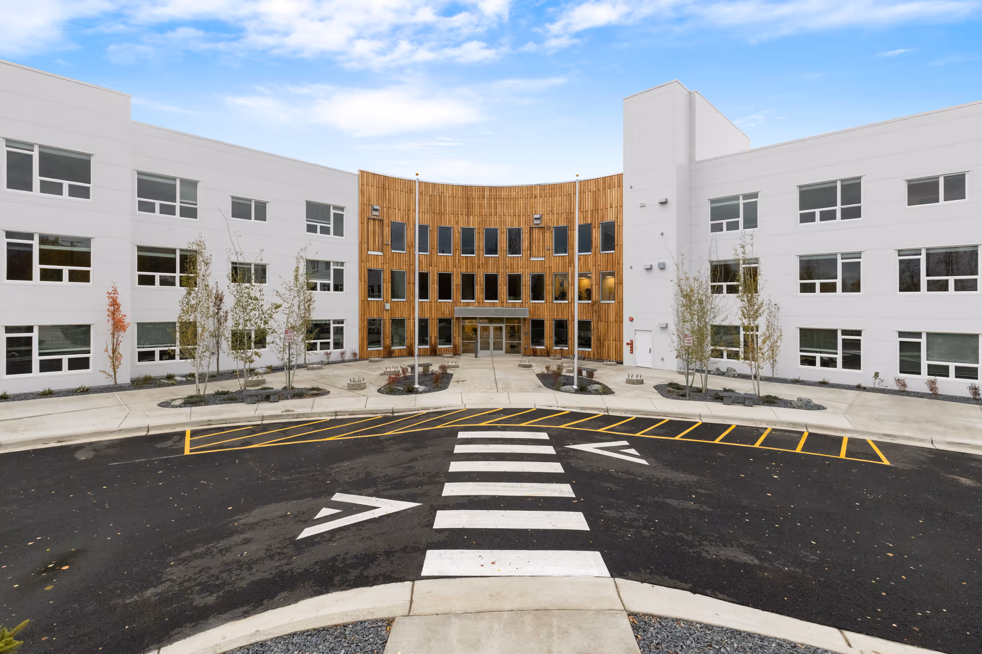 Front view of Baxter Senior Living building with wooden center entrance and parking.