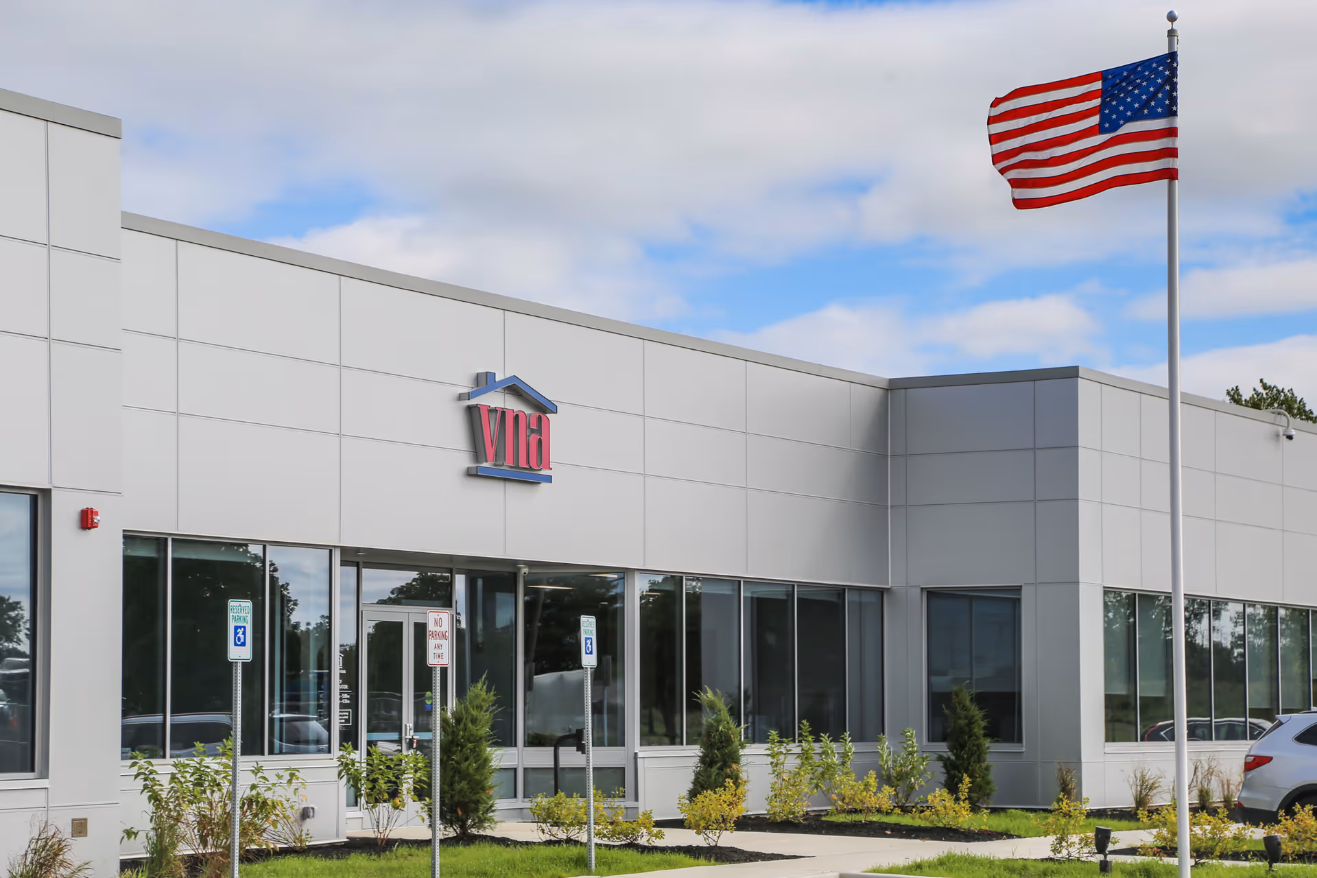 Modern medical facility exterior with a waving American flag and VNA signage
