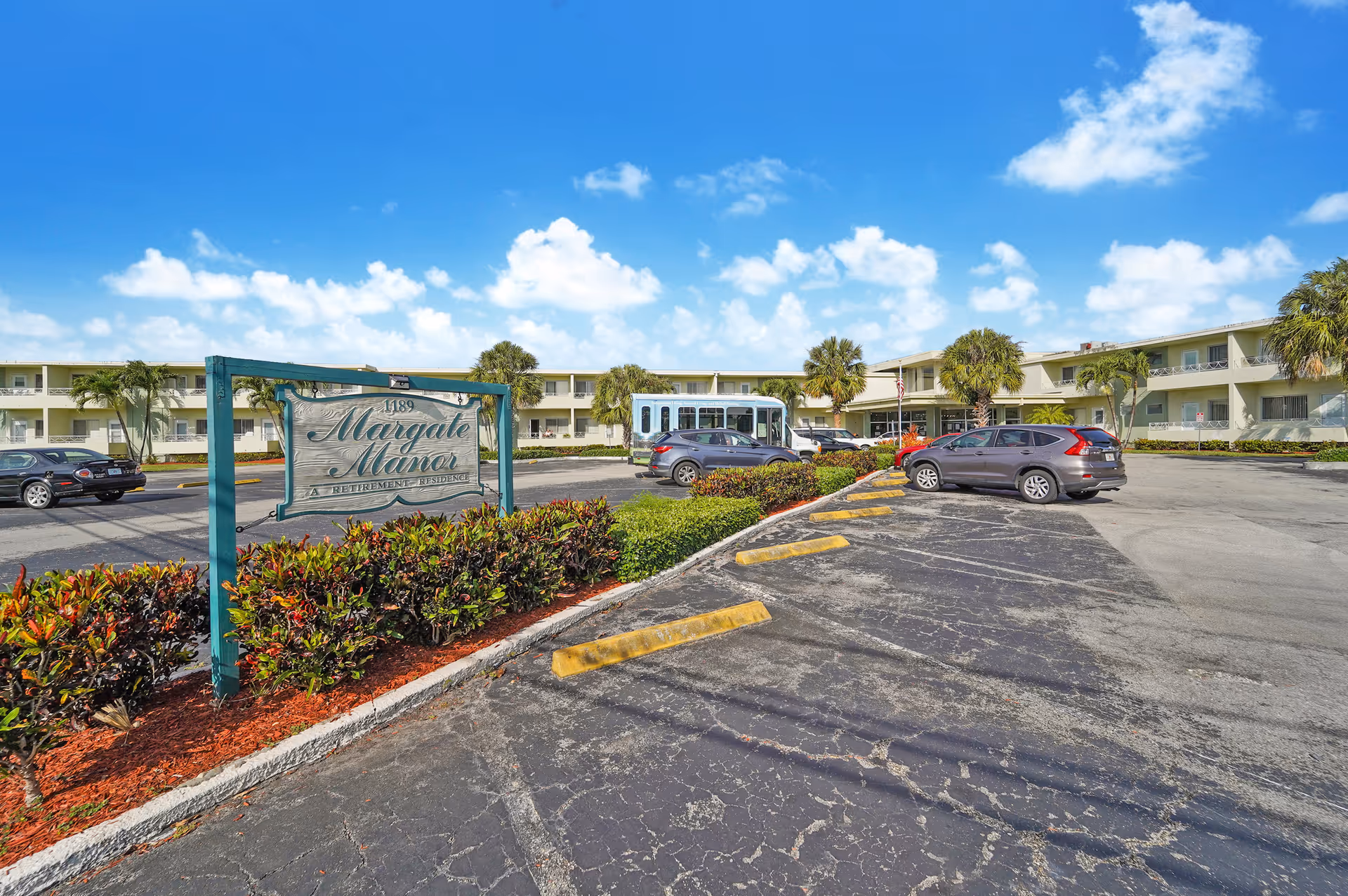 Exterior view of Oasis at Margate retirement community with parking lot and building.