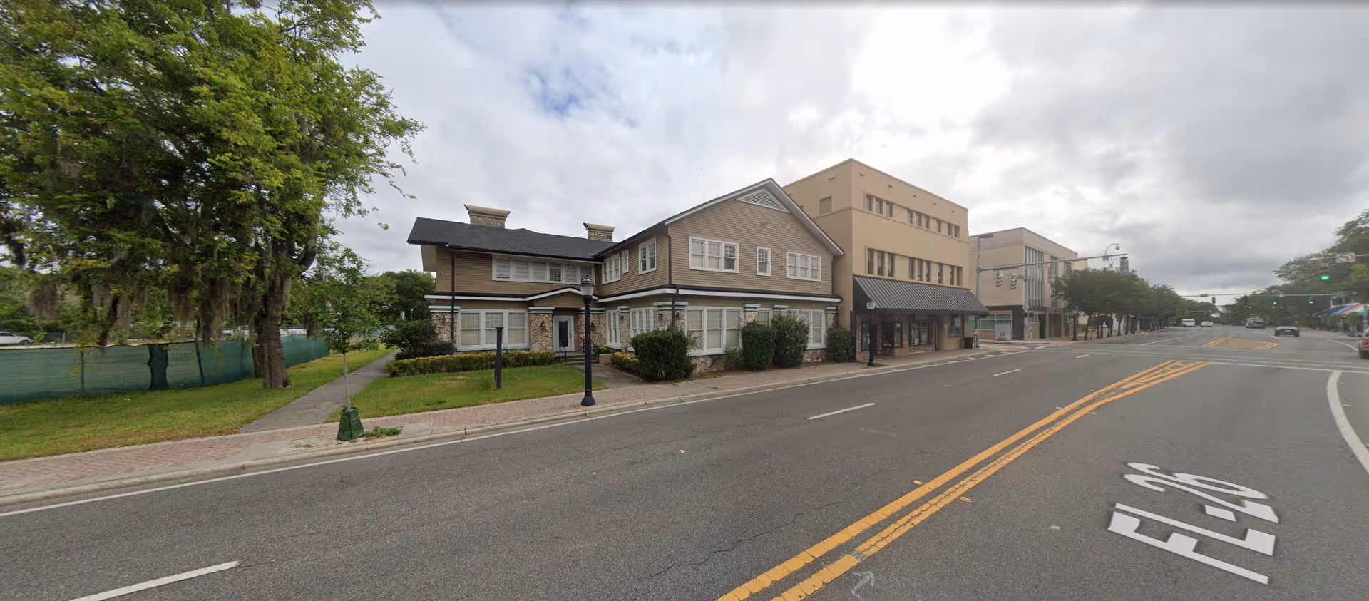 Street view of a row of senior living buildings along a tree lined sidewalk.